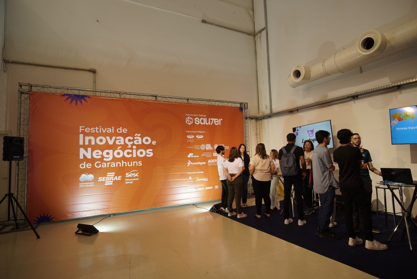 Participantes conversando em frente ao painel do Festival de Inovação e Negócios de Garanhuns
